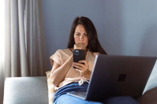 Eine junge Frau am Laptop ist besorgt und informiert sich ueber Tipps und Tricks gegen Online-Betrug.